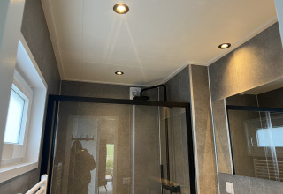 Modernes Badezimmer mit Duschkabine, Spiegel und schwarzen Akzenten in der Lodge Dijkzicht, Niederlande.