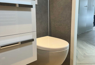 Bagno moderno con WC sospeso e mobile bianco presso Dijkzicht, Vakantiepark de Zeeuwse Parel, Paesi Bassi.