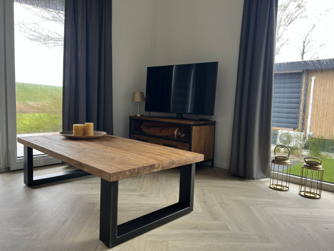 Cozy lodge living room at Dijkzicht, Vakantiepark de Zeeuwse Parel, Netherlands, with wooden table and TV.