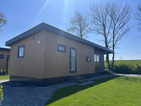 Moderno lodge Dijkzicht al Vakantiepark de Zeeuwse Parel nei Paesi Bassi con facciata in legno e prato.