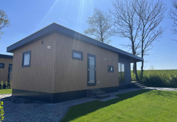 Moderno lodge Dijkzicht al Vakantiepark de Zeeuwse Parel nei Paesi Bassi con facciata in legno e prato.