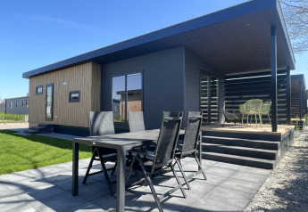 Outdoor view of Lodge Dijkzicht with modern patio and garden furniture at Vakantiepark de Zeeuwse Parel in the Netherlands.