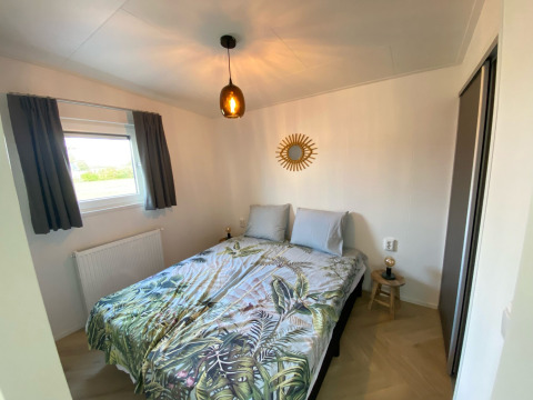 Modernes Schlafzimmer in der Dijkzicht-Lodge, Vakantiepark de Zeeuwse Parel, Niederlande, mit Doppelbett.