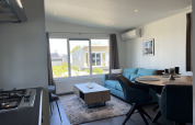 Moderne woonkamer in Lodge Noordzee, Vakantiepark de Zeeuwse Parel, Nederland, met blauwe zetel.