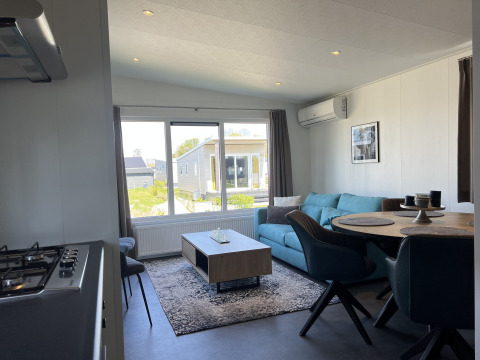 Soggiorno moderno nella Lodge Noordzee al Vakantiepark de Zeeuwse Parel, Paesi Bassi, con divano blu.