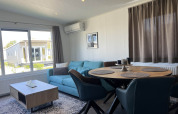 Salón moderno en la cabaña Noordzee, Vakantiepark de Zeeuwse Parel, Países Bajos, con sofá azul y mesa.