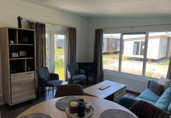 Interno moderno di un lodge Noordzee al Vakantiepark de Zeeuwse Parel nei Paesi Bassi, con ampie finestre e arredi eleganti.