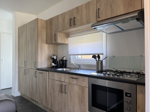 Cocina moderna en la cabaña Noordzee de Vakantiepark de Zeeuwse Parel, Países Bajos, con gabinetes de madera.