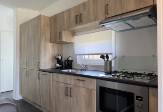 Cocina moderna en la cabaña Noordzee de Vakantiepark de Zeeuwse Parel, Países Bajos, con gabinetes de madera.