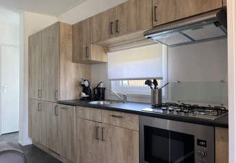 Cocina moderna en la cabaña Noordzee de Vakantiepark de Zeeuwse Parel, Países Bajos, con gabinetes de madera.