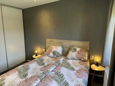 Dormitorio en la lodge Noordzee de Vakantiepark de Zeeuwse Parel, Países Bajos, con cama doble y mesitas.