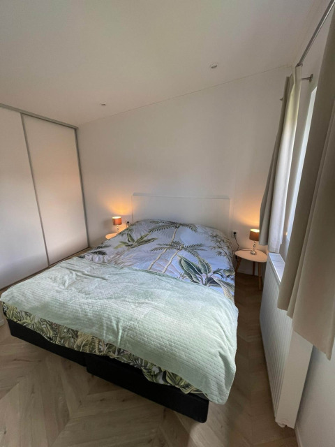 Slaapkamer in lodge Noordzee bij Vakantiepark de Zeeuwse Parel, Nederland, met tweepersoonsbed en tafeltjes.
