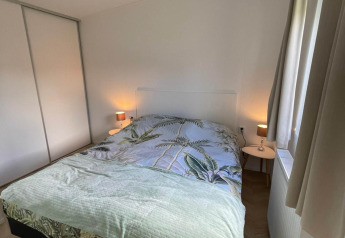 Soveværelse i lodge Noordzee ved Vakantiepark de Zeeuwse Parel med dobbeltseng og natborde.