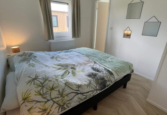 Lyst og moderne soveværelse i lodge Noordzee, Vakantiepark de Zeeuwse Parel, Nederlandene.