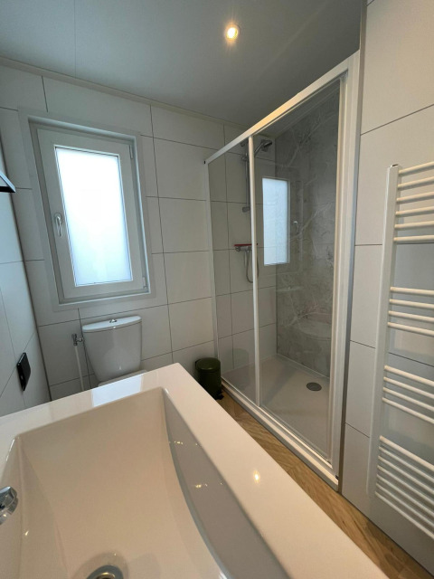 Modern bathroom with bathtub, shower, toilet, and window at Noordzee lodge in Vakantiepark de Zeeuwse Parel.