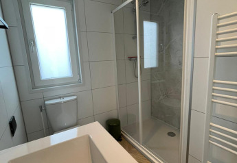 Moderne badeværelse med badekar, brusekabine, toilet og vindue på Vakantiepark de Zeeuwse Parel, Noordzee.
