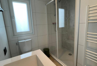 Modernes Badezimmer mit Badewanne, Dusche, Toilette und Fenster in der Noordzee Lodge, Vakantiepark de Zeeuwse Parel.