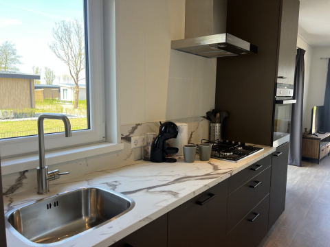 Cocina moderna en la cabaña Parkzicht en Vakantiepark de Zeeuwse Parel, Países Bajos, con vista a jardín.
