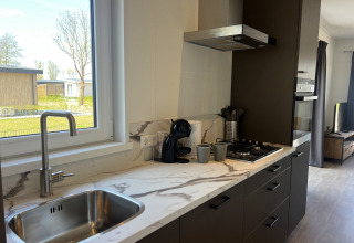 Moderne køkken ved Parkzicht-lodgen i Vakantiepark de Zeeuwse Parel, Holland, med udsigt til haven.