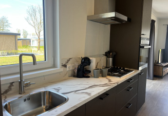 Moderne køkken ved Parkzicht-lodgen i Vakantiepark de Zeeuwse Parel, Holland, med udsigt til haven.