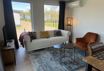 Hyggelig stue i Parkzicht-lodge på Vakantiepark de Zeeuwse Parel med moderne indretning i Holland.
