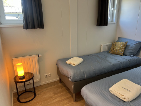 Dormitorio acogedor en Parkzicht, Vakantiepark de Zeeuwse Parel, Países Bajos, con dos camas y luz suave.