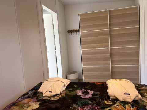 Dormitorio en la cabaña Parkzicht de Vakantiepark de Zeeuwse Parel con dos batas sobre la cama.
