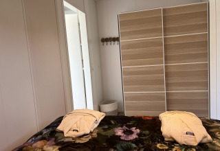 Camera da letto del lodge Parkzicht a Vakantiepark de Zeeuwse Parel con due accappatoi sul letto.