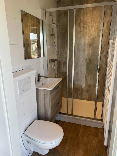 Baño moderno con ducha, inodoro suspendido y lavabo en una cabaña de Parkzicht, Vakantiepark de Zeeuwse Parel.