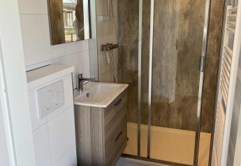 Moderne badeværelse med bruser, væghængt toilet og håndvask i en lodge på Parkzicht, Vakantiepark de Zeeuwse Parel.