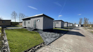 Cabañas modernas en Oosterschelde, Vakantiepark de Zeeuwse Parel, Países Bajos, bajo un cielo azul claro.