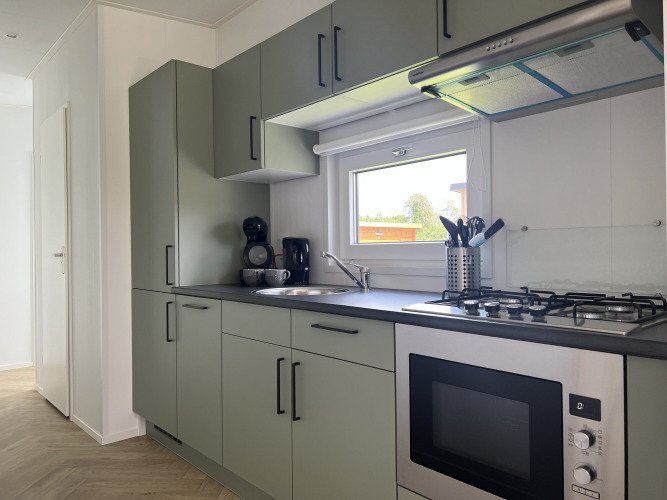 Modern kitchen at Oosterschelde lodge in Vakantiepark de Zeeuwse Parel, Netherlands, with stove and window.