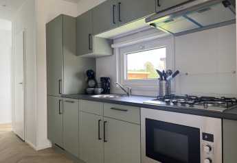 Moderne keuken in Oosterschelde lodge bij Vakantiepark de Zeeuwse Parel, Nederland, met oven en raam.