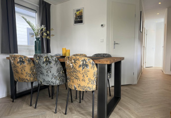 Moderne eetkamer in een lodge op Vakantiepark de Zeeuwse Parel met bloemenstoelen en houten tafel.