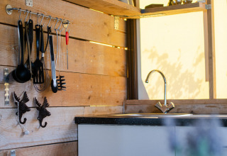 Coin cuisine moderne dans une tente lodge safari avec murs en bois, micro-ondes et cafetière.
