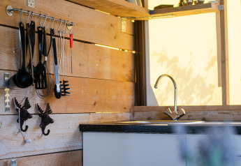 Angolo cucina moderno in una tenda lodge safari con rivestimenti in legno, microonde e macchina da caffè.