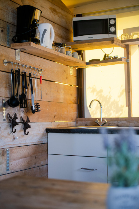 Modern kitchenette in a safari tent lodge with wood paneling, microwave, and coffee maker.
