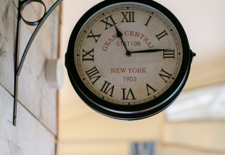 Reloj de estilo retro con números romanos colgado en la pared de una tienda safari en Tentlodge.