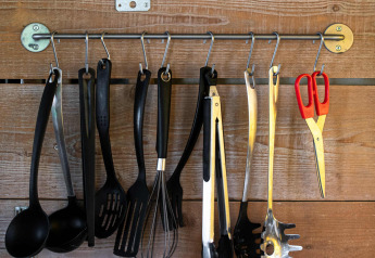 Ustensiles de cuisine accrochés à des crochets sur un mur en bois sous une étagère dans une tente safari Tentlodge.