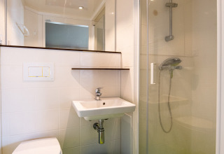 Bagno moderno nella tenda safari Tentlodge con pavimento verde, doccia, WC, lavandino e grande specchio.