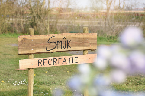 Cartel de madera con 'Smûk Recreatie' en un parque vacacional en Frisia, Países Bajos, sobre césped.