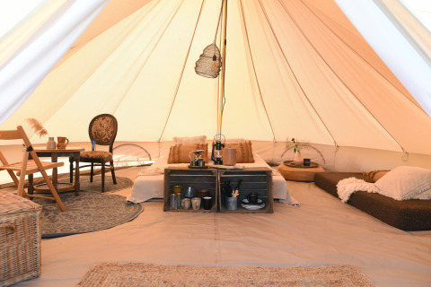 Interno di tenda glamping accogliente con letto e zona relax a Smûk Recreatie, Frisia, Paesi Bassi.