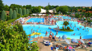 Gran piscina repleta de huéspedes en Camping Bella Italia, un parque vacacional en Véneto, Italia, en un día soleado.