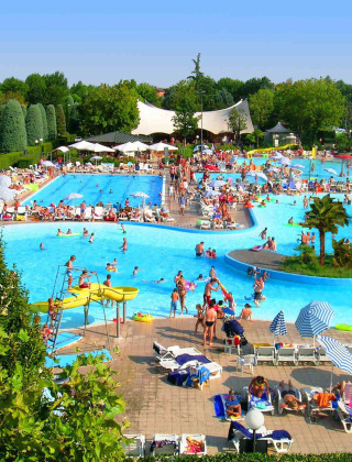 Gran piscina repleta de huéspedes en Camping Bella Italia, un parque vacacional en Véneto, Italia, en un día soleado.