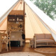 Indretning af en luksuriøs safari-telt med træmøbler, sofa og tekøkken hos Smûk Grutte Bell Tent.