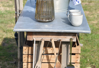 Draußen Küchenbereich mit Blumen, Metalleimer, Tassen und hängenden Utensilien an einem Zelt in den Niederlanden.