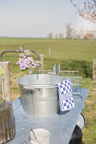 Outdoor-Spülstation mit Metalleimer und blauem Geschirrtuch bei Smûk Grutte Bell Tent, Niederlande.