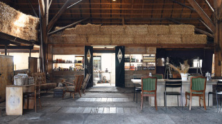 Intérieur de grange chaleureux avec bottes de foin et meubles anciens à Smûk Recreatie en Frise.
