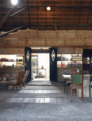 Intérieur de grange chaleureux avec bottes de foin et meubles anciens à Smûk Recreatie en Frise.