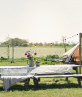 Table de pique-nique avec fleurs, tente et vélos sur une prairie au parc Smûk Recreatie, Frise, Pays-Bas.